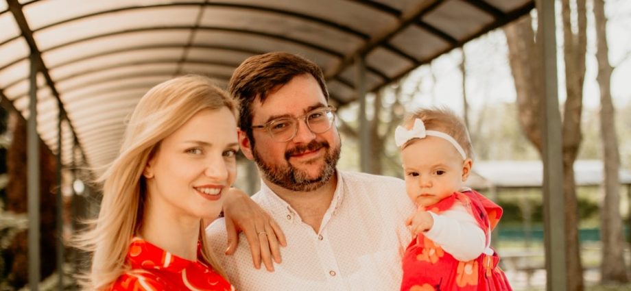 a man and woman holding a baby under a shelter